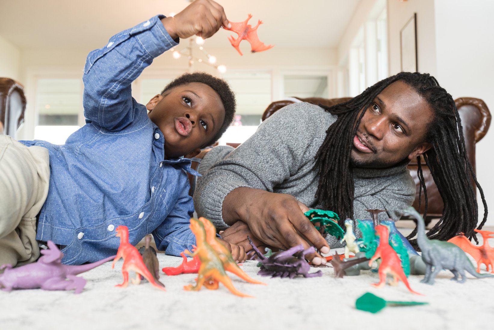 African American boy playing dinosaurs with dad